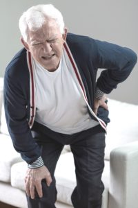 a man winces as he grabs his hip